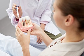 Dentist pointing to a dental implant model that a patient is holding
