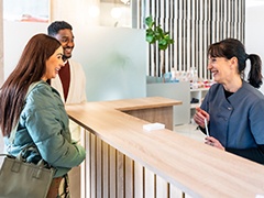 Dental receptionist smiling at couple in lobby