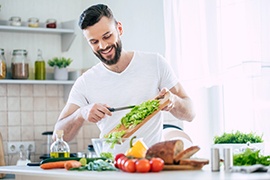 Man smiling while preparing healthy meal in kitchen
