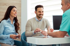 Dentist and couple talking in dental office