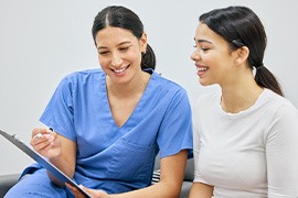 Dental assistant and patient smiling while reviewing information