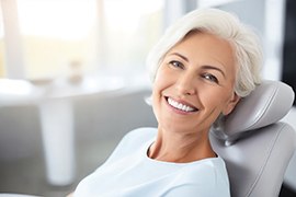 Woman with white hair in dentist’s chair smiling