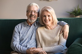 Man and woman on a green couch holding hands and smiling