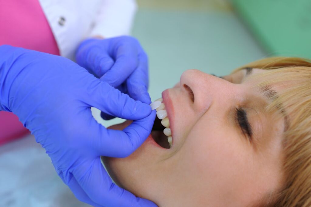 A woman getting her new veneers attached by a dentist